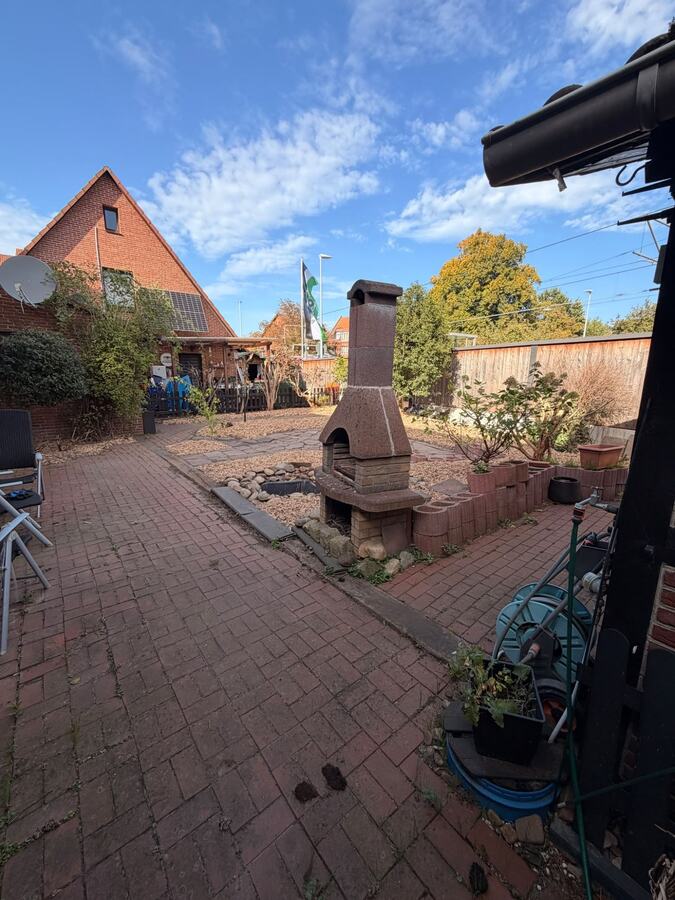 Fertiger Garten mit freiem Weg, Grillkamin und Hackschnitzel-Beeten nach der Gartensanierung
